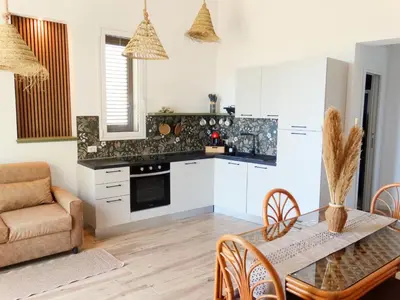 a kitchen with white cabinets and a table and chairs at La Maschera di Giano, case vacanza vista mare in Palermo