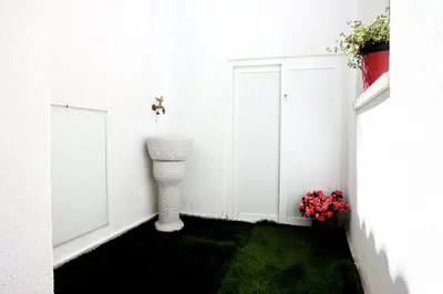 a white room with green grass and a vase of flowers at Ivi's House in Palermo