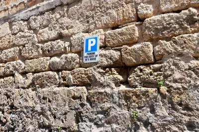 a blue parking sign on a stone wall at Ivi's House in Palermo