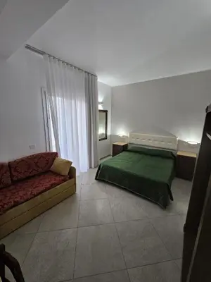 a bedroom with a green bed and a couch at Alle Porte di San Vito in San Vito lo Capo