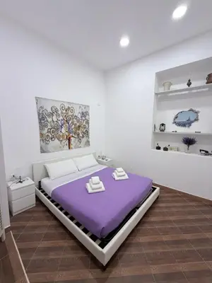 a bedroom with a purple bed and a painting on the wall at Violet House in Palermo