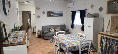 a kitchen and living room with a table and a refrigerator at la casetta di nin e gian mondello in Palermo