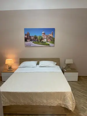 a bedroom with a large white bed with two lamps at La casetta del sole in Palermo