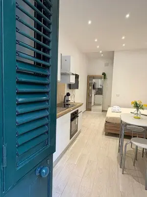 a kitchen and living room with a green door at LeRoccheRoom in Monreale