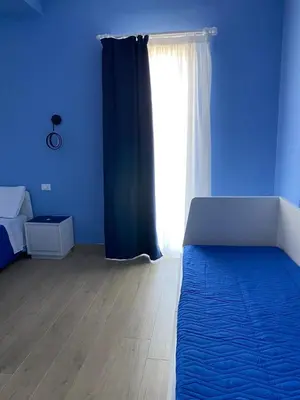 a blue room with a bed and a window at MARE Suite in Palermo