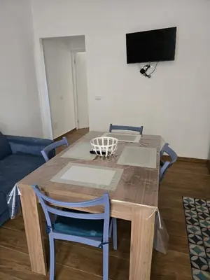 a dining room table with chairs and a television at Nonna Franca GuestHouse in Isola delle Femmine