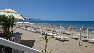 a beach with chairs and umbrellas and the ocean at Dimora Solemar-Mareluna village in Campofelice di Roccella