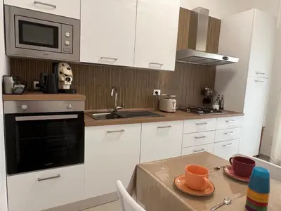 a kitchen with white cabinets and a table with cups on it at TramQuility House in Palermo