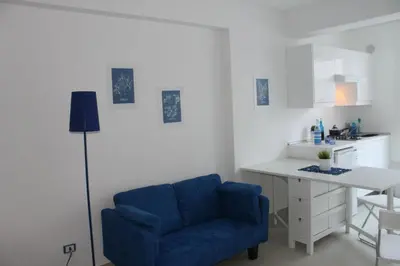 a living room with a blue chair and a desk at Mondello Suites FLH - Riflessi in Palermo
