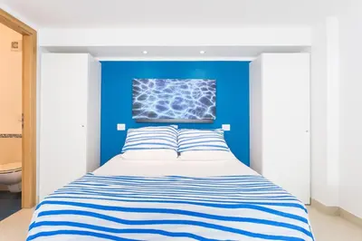 a bed in a room with a blue wall at Mondello Suites FLH - Riflessi in Palermo