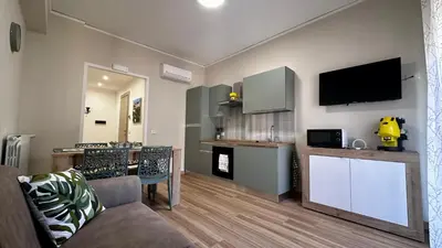 a living room with a couch and a kitchen at Albachiara Apartment vicino al mare di Capaci in Capaci
