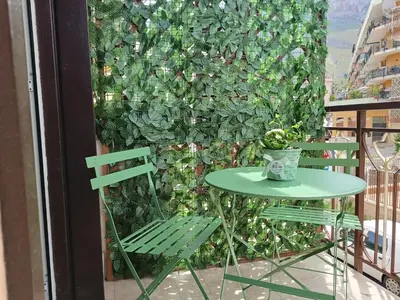 a green wall with a table and a chair on a balcony at Albachiara Apartment vicino al mare di Capaci in Capaci