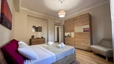 a bedroom with a large bed and a chair at Albachiara Apartment vicino al mare di Capaci in Capaci