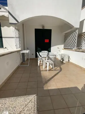 a patio with a table and chairs and a black door at Le Palme House in Isola delle Femmine