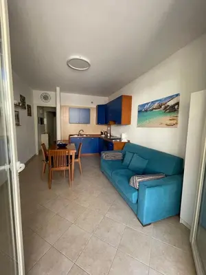 a living room with a blue couch and a table at Le Palme House in Isola delle Femmine