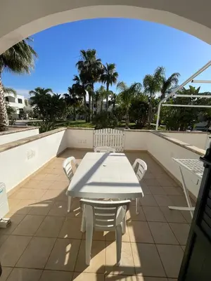 a white table and chairs on a balcony with palm trees at Le Palme House in Isola delle Femmine
