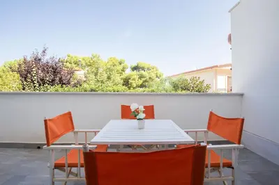 a table with orange chairs and a vase with flowers on it at Mondello suites FLH - Posidonia in Palermo