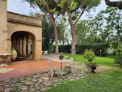 a dog sitting on a table in a garden at Villa Kinisia, antica dimora siciliana in Cinisi
