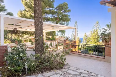 a pergola on a house with a tree at Villa Azzurra in Scopello