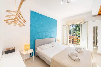 a white bedroom with a blue accent wall at Villa Azzurra in Scopello