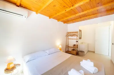 a bedroom with a white bed and a wooden ceiling at Villa Azzurra in Scopello