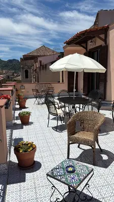 a patio with a table and chairs and an umbrella at Casa Vacanze Mazzini, amazing Rooftop! in Termini Imerese