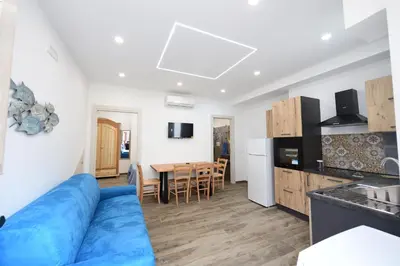 a living room with a blue couch and a kitchen at Ummi Taliari in Terrasini