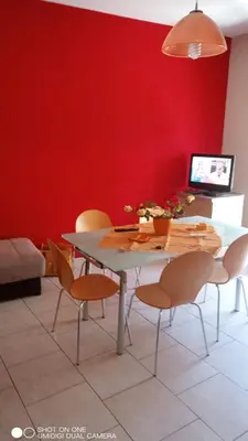 a dining room with a table and chairs against a red wall at Nicitra in Isola delle Femmine