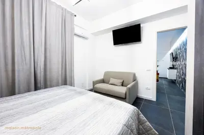 a bedroom with a bed and a chair and a television at Calatafimi House in Palermo
