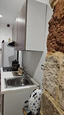 a kitchen with a sink next to a stone wall at La Corte Di San Basilio palermo in Palermo