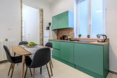 a kitchen with green cabinets and a table and chairs at Suites Santa Cecilia in Palermo