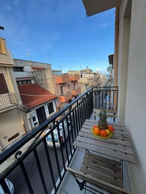 a wooden table with a bowl of fruit on a balcony at Casa Miramara Sicilia in Balestrate