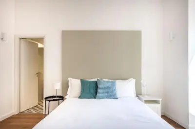 a white bedroom with a large white bed with blue pillows at Ci' Capo Apartments by Wonderful Italy in Palermo