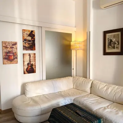a white couch in a living room with paintings at Sedie Volanti Classy Home in Palermo