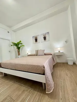 a white bedroom with a bed and a wooden floor at TerrAmata in Terrasini