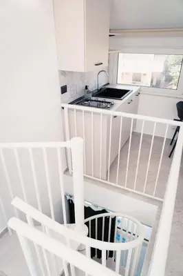 a white kitchen with a spiral staircase in a room at Acqua Marina Balestrate in Balestrate