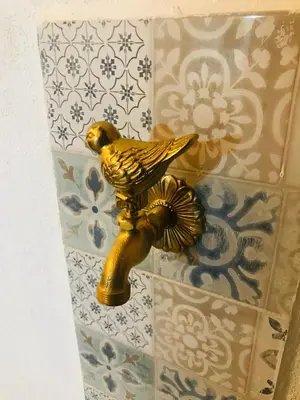 a gold bird statue on a tiled wall at D'anthoine apartment in Palermo