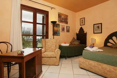 a living room with a bed and a desk and a chair at Giardino degli Ulivi in Palermo