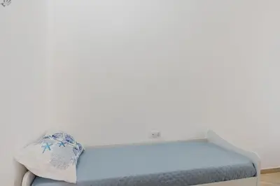 a white bedroom with a bed and a window at Perla Marina in Trappeto