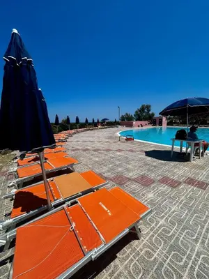 a row of orange lounge chairs next to a swimming pool at Casetta mia Seaside in Buonfornello