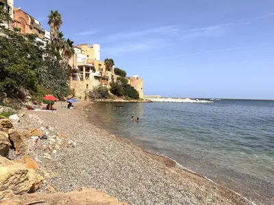a rocky beach with people swimming in the water at Fantastic, sea view apartment via Duchessa in Castellammare del Golfo