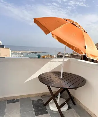 a wooden chair with an umbrella on a balcony at Fantastic sea & harbour view Nino Bixio in Castellammare del Golfo
