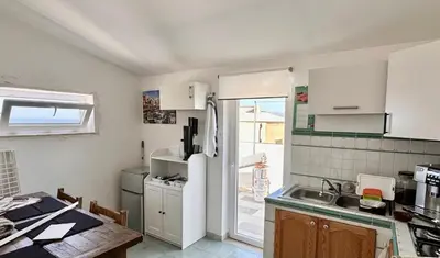 a kitchen with a refrigerator and a table in it at Fantastic sea & harbour view Nino Bixio in Castellammare del Golfo