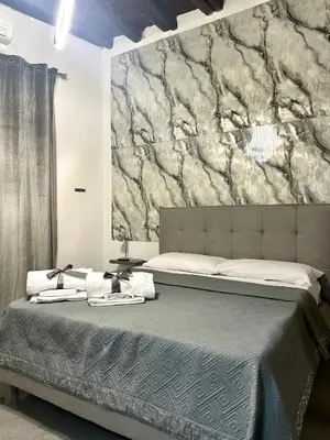 a bedroom with a bed and a marble wall at Shamà rooms in Palermo