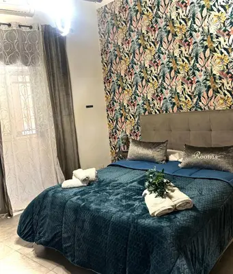 a bedroom with a large bed with a blue blanket at Shamà rooms in Palermo