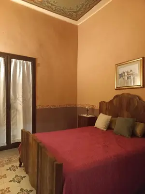 a bedroom with a bed with a red blanket and a window at Casa Mazzini in Carini