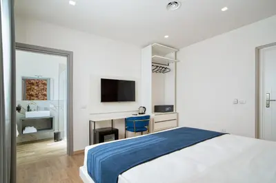 a white bedroom with a bed and a tv at Ella Suites Apartments in Terrasini