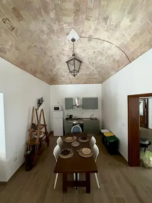 a dining room with a table and a kitchen at Dimora Donna Carmela in Capaci