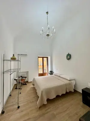 a white bedroom with a bed and a chandelier at Dimora Donna Carmela in Capaci
