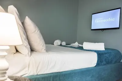 a bedroom with a white bed with a flat screen tv at Foresteria del Genio - Luxury Suites & Urban Spa in Palermo